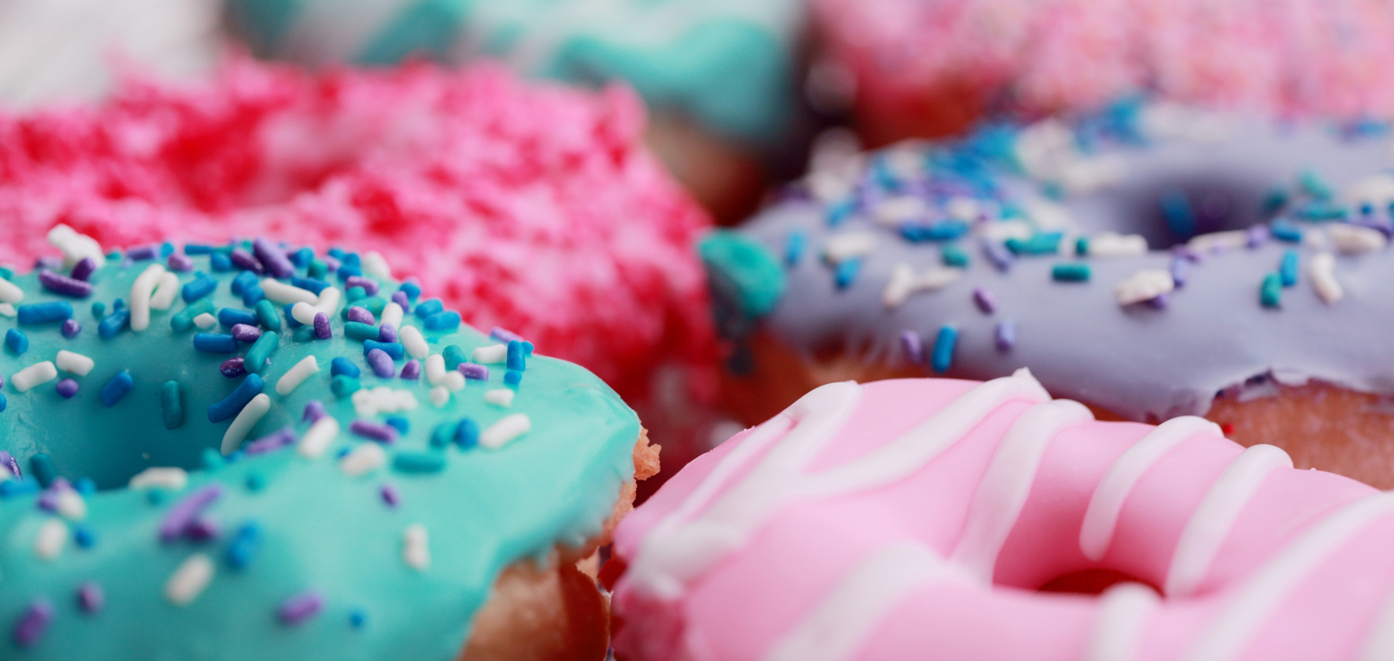 Row of three donuts on a blue table.